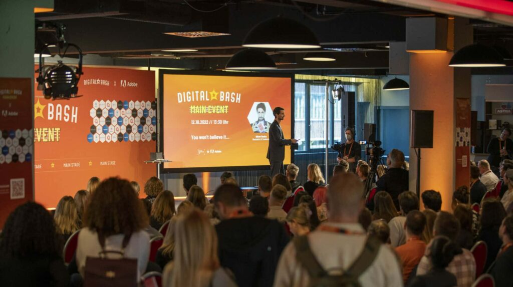 Oliver Henke auf der Main Stage beim Digital Bash – sein Name steht auf der Leinwand des Veranstalters